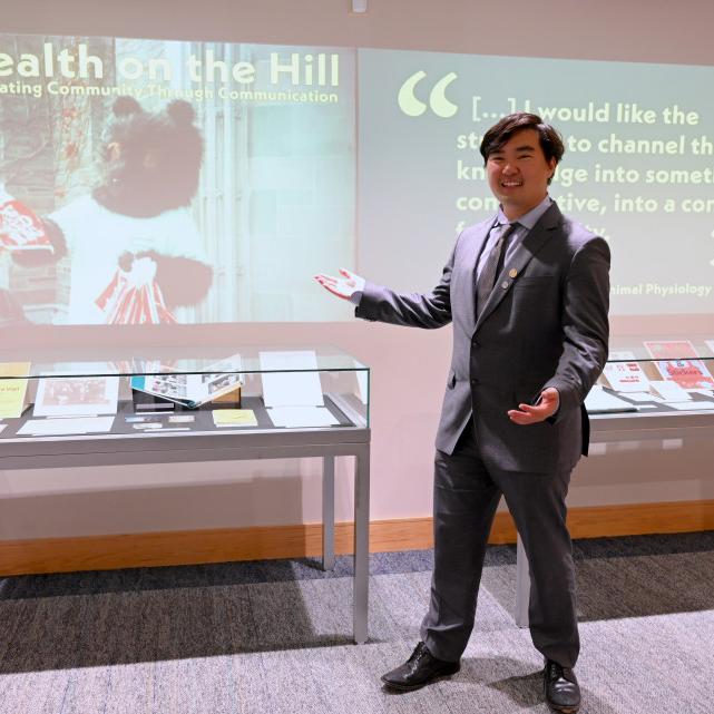Person in suit presenting a display case and an image projected on a wall