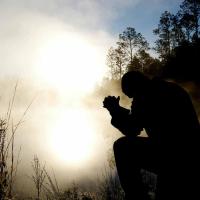 Silhouette of person kneeling by a pond