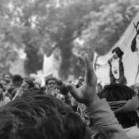 Black and white image of a rally; people around a flag