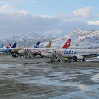 Planes in a row with snow-covered mountains behind them.