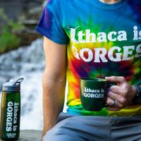 a person wearing an Ithaca is Gorges tshirt with mug and water bottle