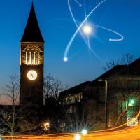 An artist's rendition of an atom in the sky next to McGraw Tower on Cornell's campus.