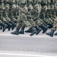 Soldiers dressed in army camouflage march in formation 