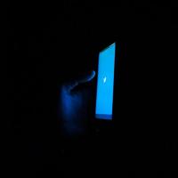 Blue phone screen glows against a dark background