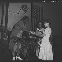 Black and white historic photo of one person giving an award to another on a stage