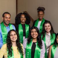 Seven people wearing green honor stoles