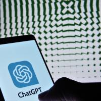 Small screen shows ChatGPT/OpenAI logo with a large screen showing a pattern in the background