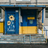 Doorway to a building, painted in bright blue and yellow with sunflowers