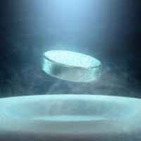 metal puck levitates above a slightly pitted white surface