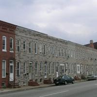 A long line of two-story rowhouses, all one color except for one red brick house.
