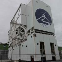 The side of the telescope, showing the logo with "FYST" and "CCAT" and a line drawing of a road leading up a mountain