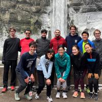 Several people in running clothes pose at the base of a waterfall