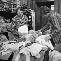  Two women sorting a big box of used clothing
