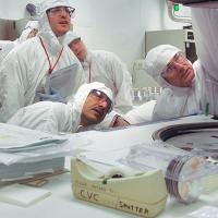  People in white protective gear and goggles, in a lab