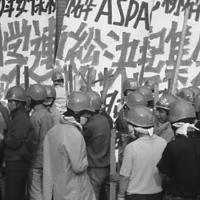  Japanese with helmets on in front of a  protest sign in Japanese