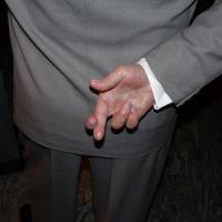  Man in business suit holding crossed fingers behind his back