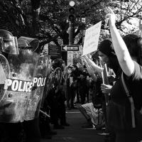  A line of police with shields stands against protesters
