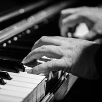  A black and white photo of two hands playing a piano