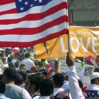  Image of a rally with an American flag and a sign saying &quot;love&quot;