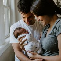  A father and a mother smiling at a baby she is holding