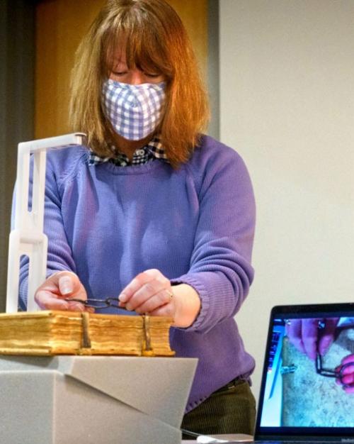 Person wearing mask works with an old book