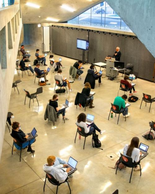 Students, sitting far apart, meet for class in Milstein Hall