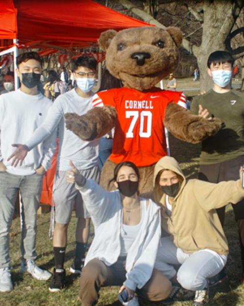 Seven students and the bear mascot, looking happy