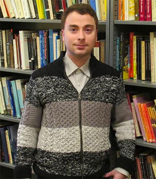 		Kevin Bloomfield in front of a book stack. 
	