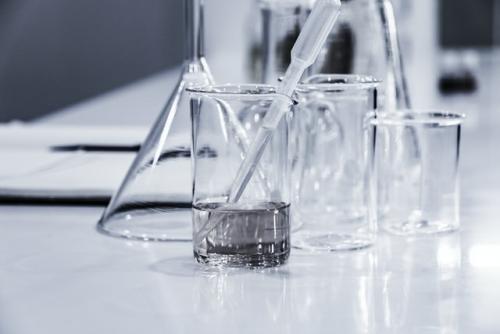 Glass beakers on a table, one partially filled with liquid