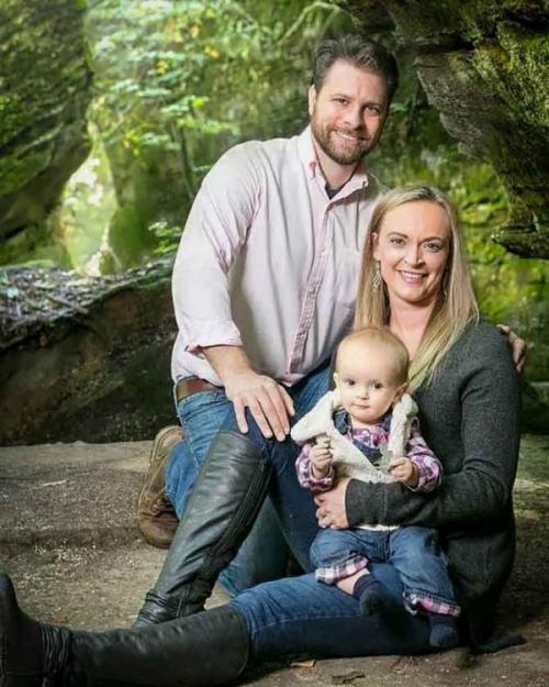 husband, wife and baby in a park