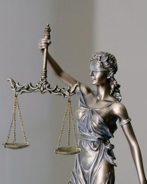 A blindfolded bronze woman in a toga holding a set of scales