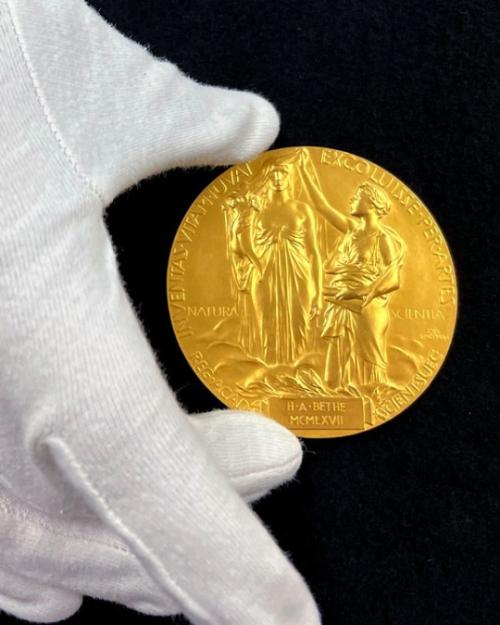 Gloved hand holding a gold medal