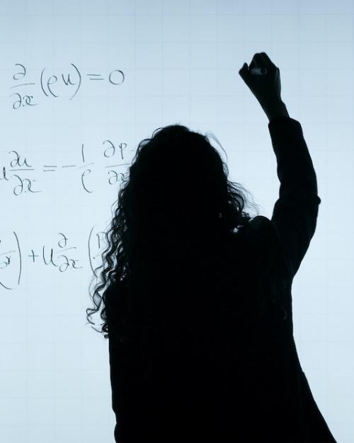 		Person silhouetted against a white background, writing equations on a board
	