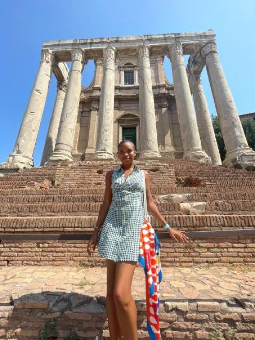 Female student standing in front of ancient ruin 
