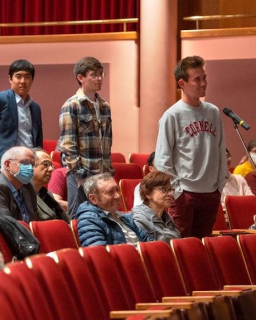 People line up in an auditorium for a chance to speak at a microphone
