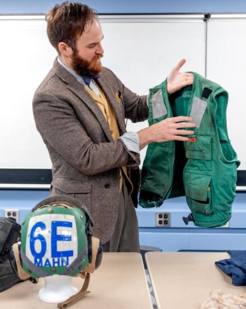 A person holds up a green vest -- a military flack jacket from the U.S. Navy