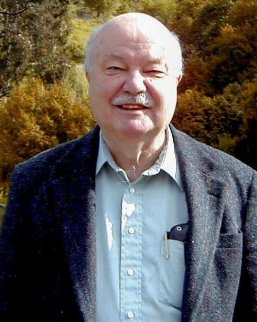 		White haired, mostly bald, with a mustache and a tweed jacket and a smile
	