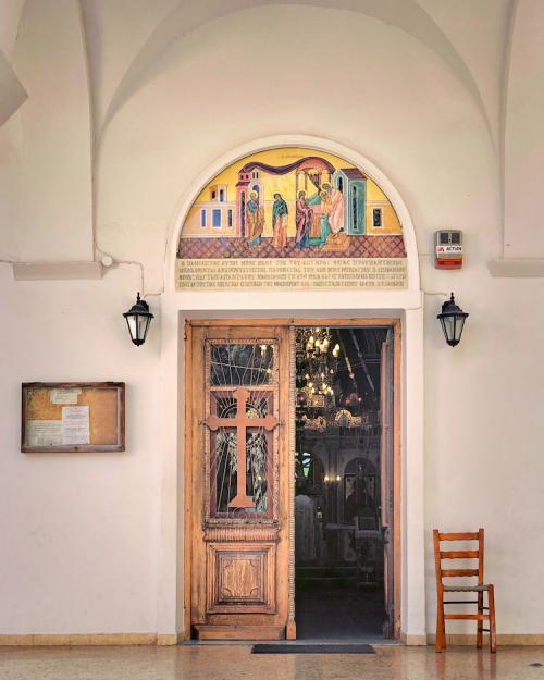 Doorway decorated with a wooden cross and colorful painting of four figures