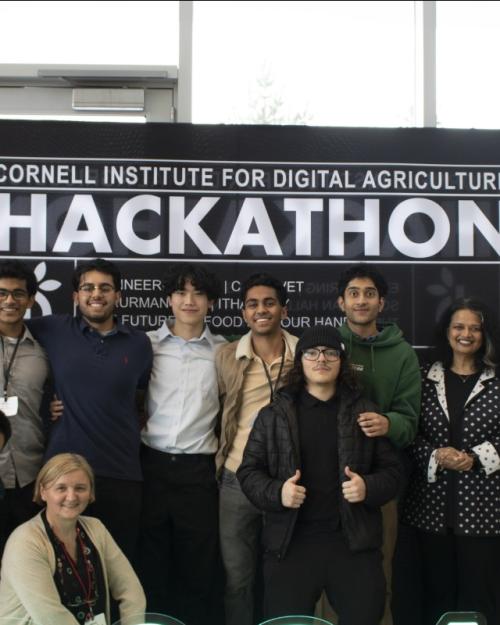 		Several people pose in front of a sign that says "HACKATHON"
	