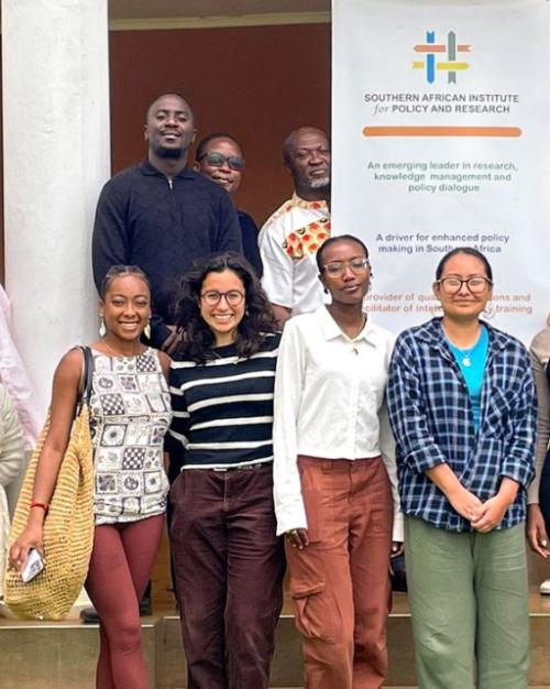 		Several people pose around a sign for "Southern African Policy Institute"
	