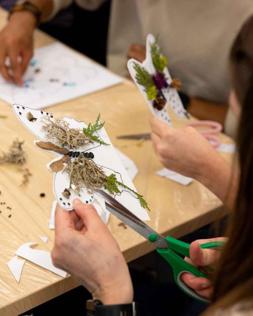 person creating a butterfly from paper and natural objects