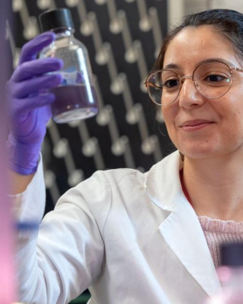 		Person in lab coat holding a glass bottle
	