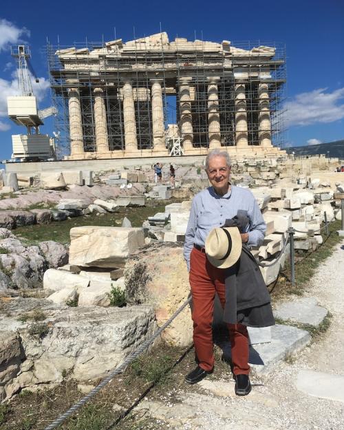 Person standing on a path in front of columned ruins of the Parthenon 
