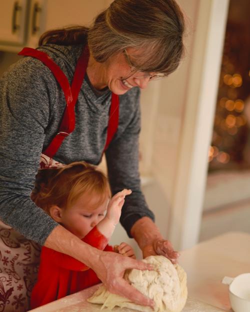 Person helps a small child knead bread dough