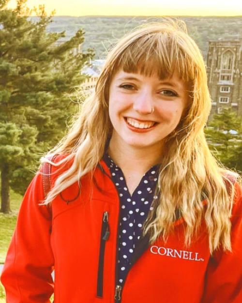 		Lorlei Boyd, long blond hair and in a Cornell jacket, smiling with Libe Slope trees behind her
	
