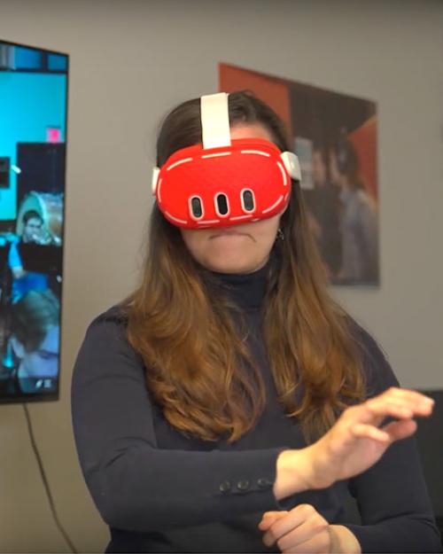 Person wearing a red virtual reality headset and gesturing with her arms