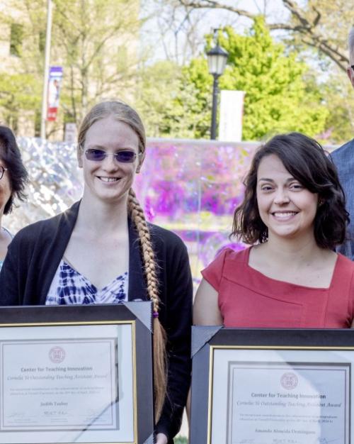 		Award winners holding framed certificates smiling at the camera with other people next to them also smiling
	