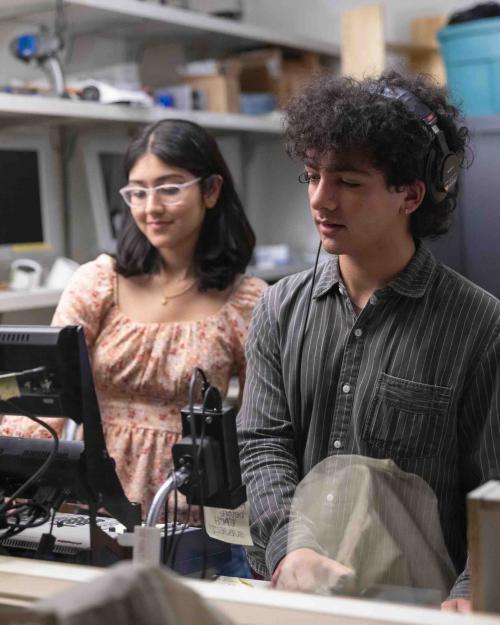 		two people working behind a computer
	