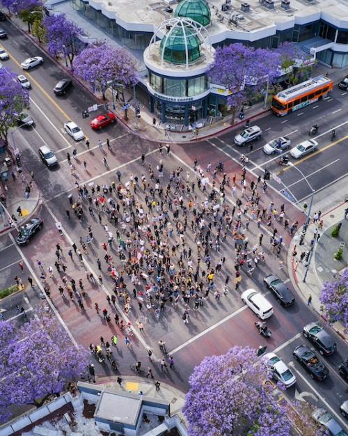 		A crowd gathering on a city intersection, seen from above
	