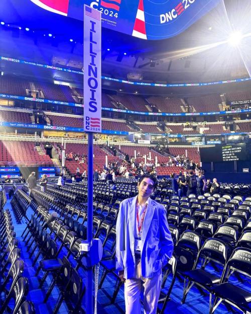 Person standing on the floor an enormous convention center that's mostly empty, next to a banner that says "Illinoi"
